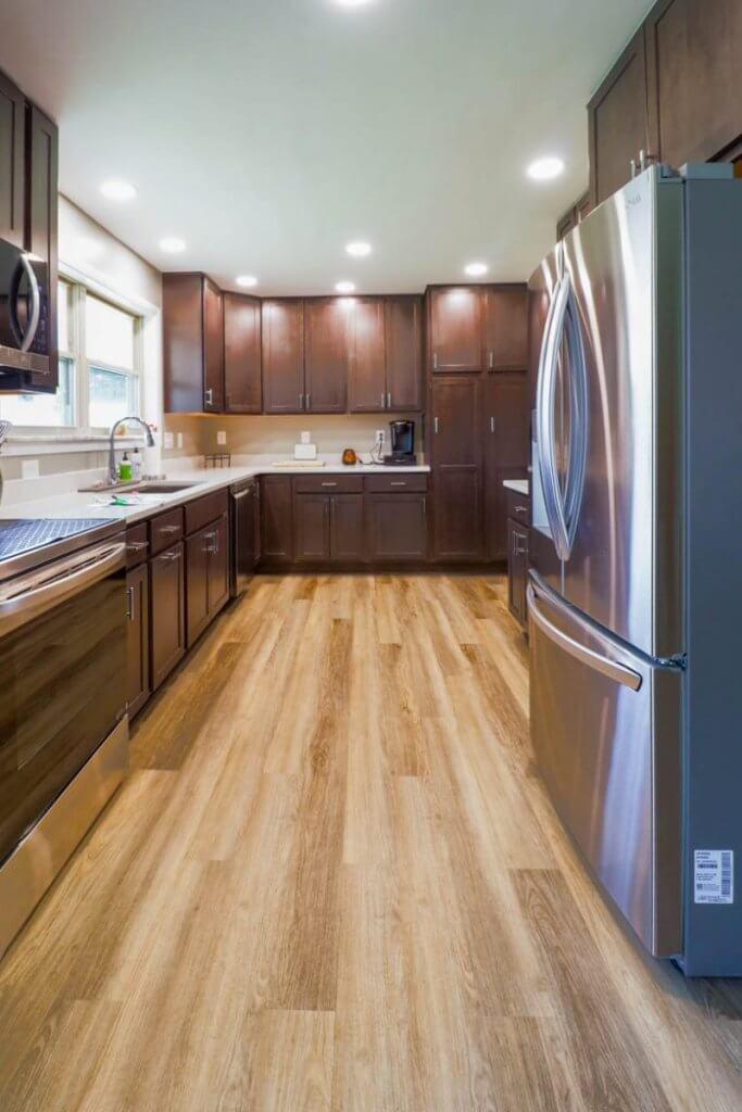 Completed kitchen remodel by Odd Fellows Contracting in St. Joe, MI featuring dark wood cabinets and stainless refrigerator.
