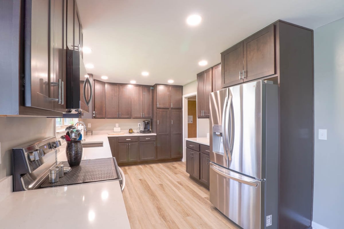 Finished kitchen remodel by Odd Fellows Contracting in St. Joe, MI with dark wood cabinets and stainless steel appliances.