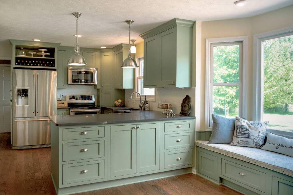 Kitchen remodel with green cabinets, island storage and window bench seating in Williamston MI by Odd Fellows Contracting