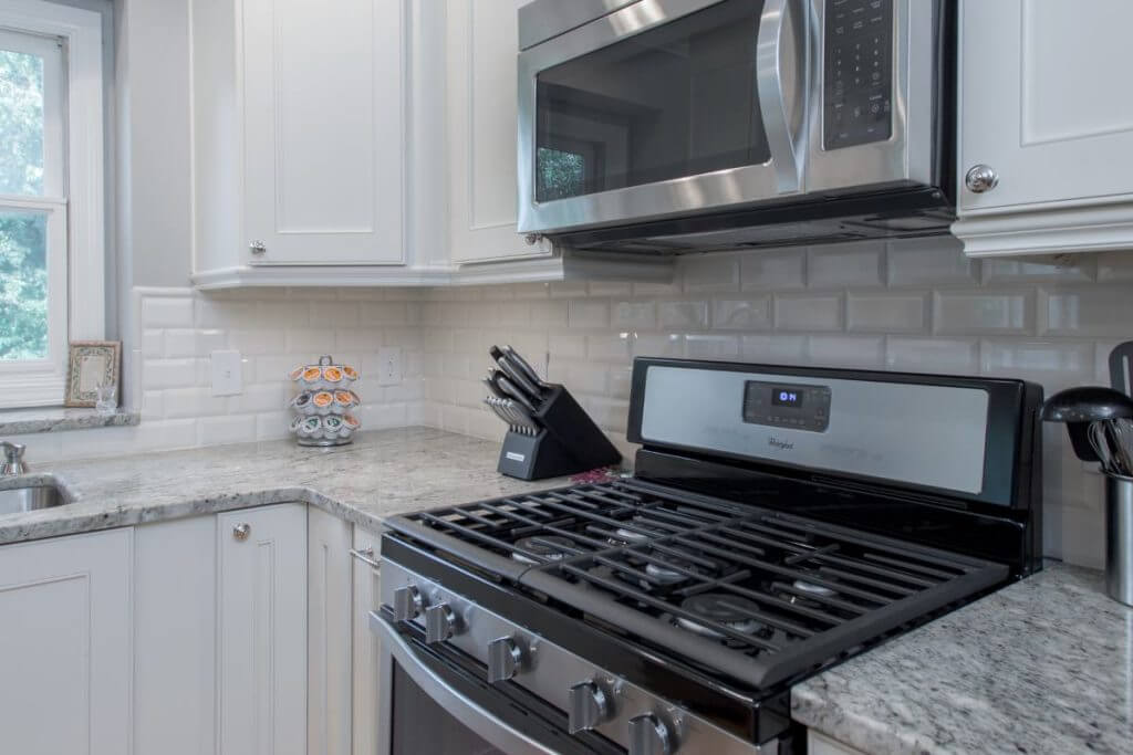 Gas cooktop and microwave with subway tile backsplash in Okemos MI kitchen remodel by Odd Fellows Contracting