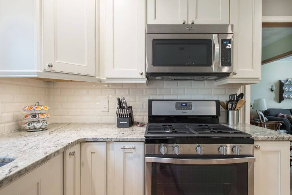 Kitchen cooking area with subway tile backsplash and granite countertops in Okemos MI by Odd Fellows Contracting