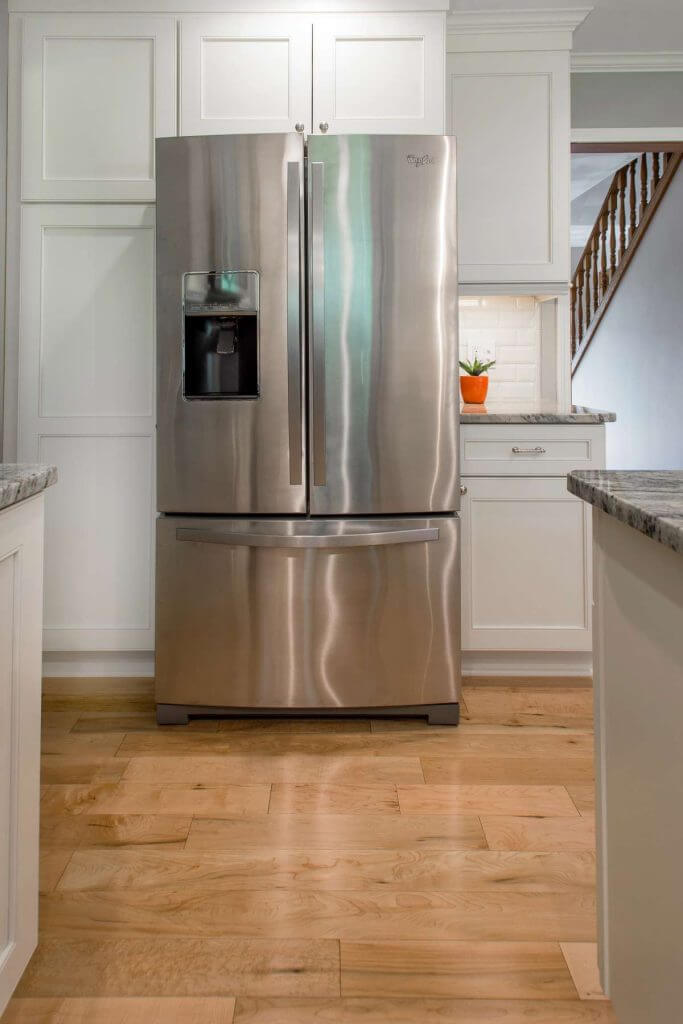 Stainless steel refrigerator surrounded by custom cabinets in Okemos MI kitchen remodel by Odd Fellows Contracting