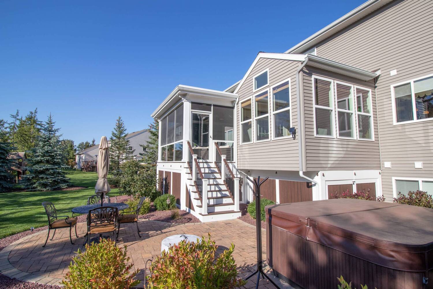 exterior view of home with screened three season room addition and patio by Odd Fellows Contracting Okemos MI