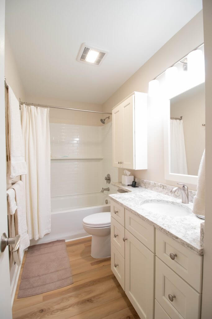 Bathroom remodel with white vanity, granite countertop, and tub shower by Odd Fellows Contracting in Lansing, MI.