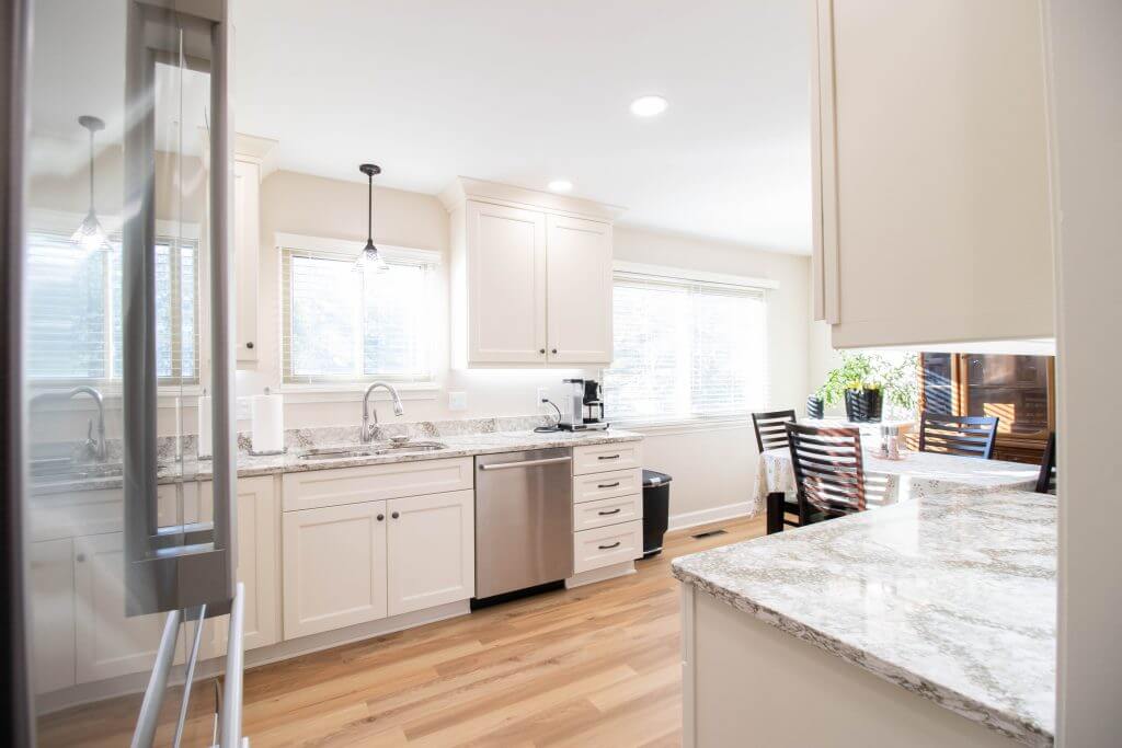Bright kitchen renovation with updated cabinets, granite counters, and open dining space by Odd Fellows Contracting in Lansing, MI.