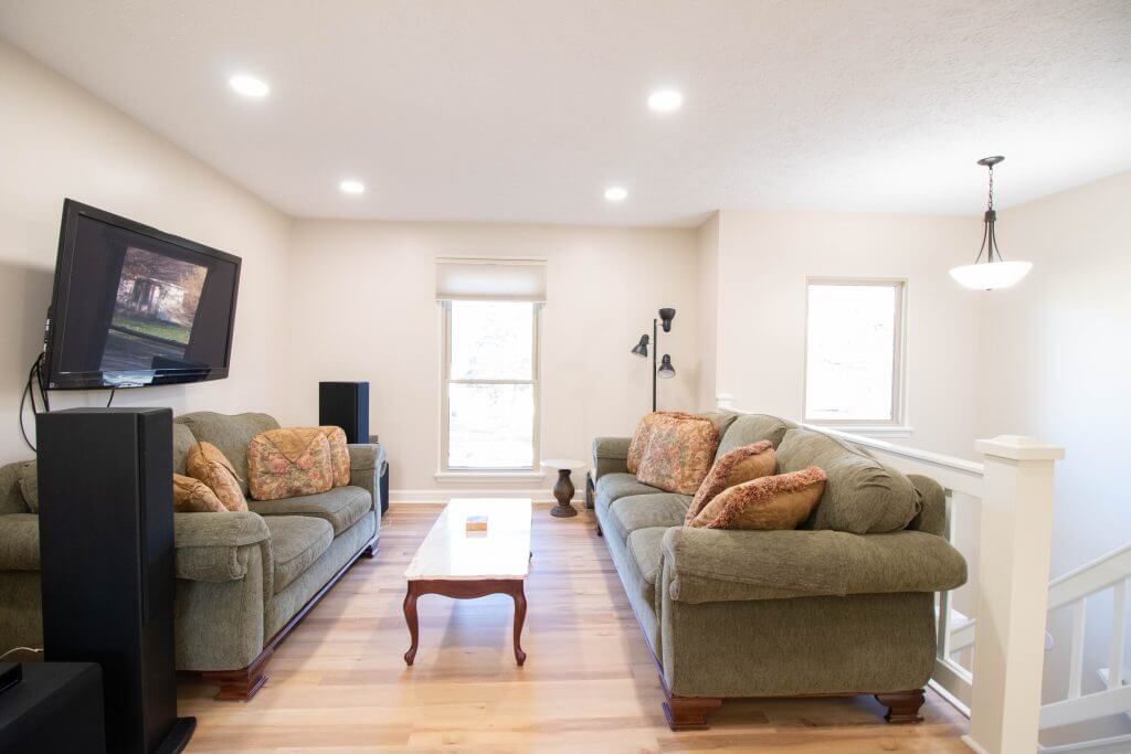 Living room remodel with hardwood floors, seating area, and updated lighting by Odd Fellows Contracting in Lansing, MI.