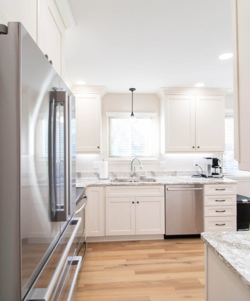 Remodeled kitchen with white cabinets, granite countertops, and stainless appliances by Odd Fellows Contracting in Lansing, MI.