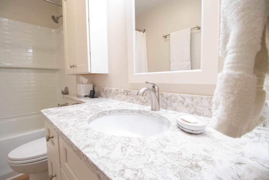 Updated bathroom vanity with granite countertop and modern fixtures by Odd Fellows Contracting in Lansing, MI.