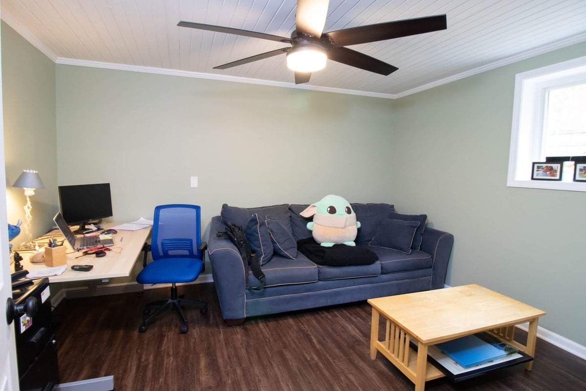 Basement bedroom remodel with workspace, seating, and finished flooring by Odd Fellows Contracting in Lansing, MI.