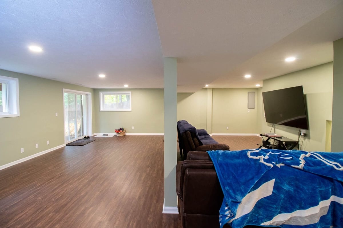 Basement remodel with open entertainment area, seating, and modern flooring by Odd Fellows Contracting in Lansing, MI.