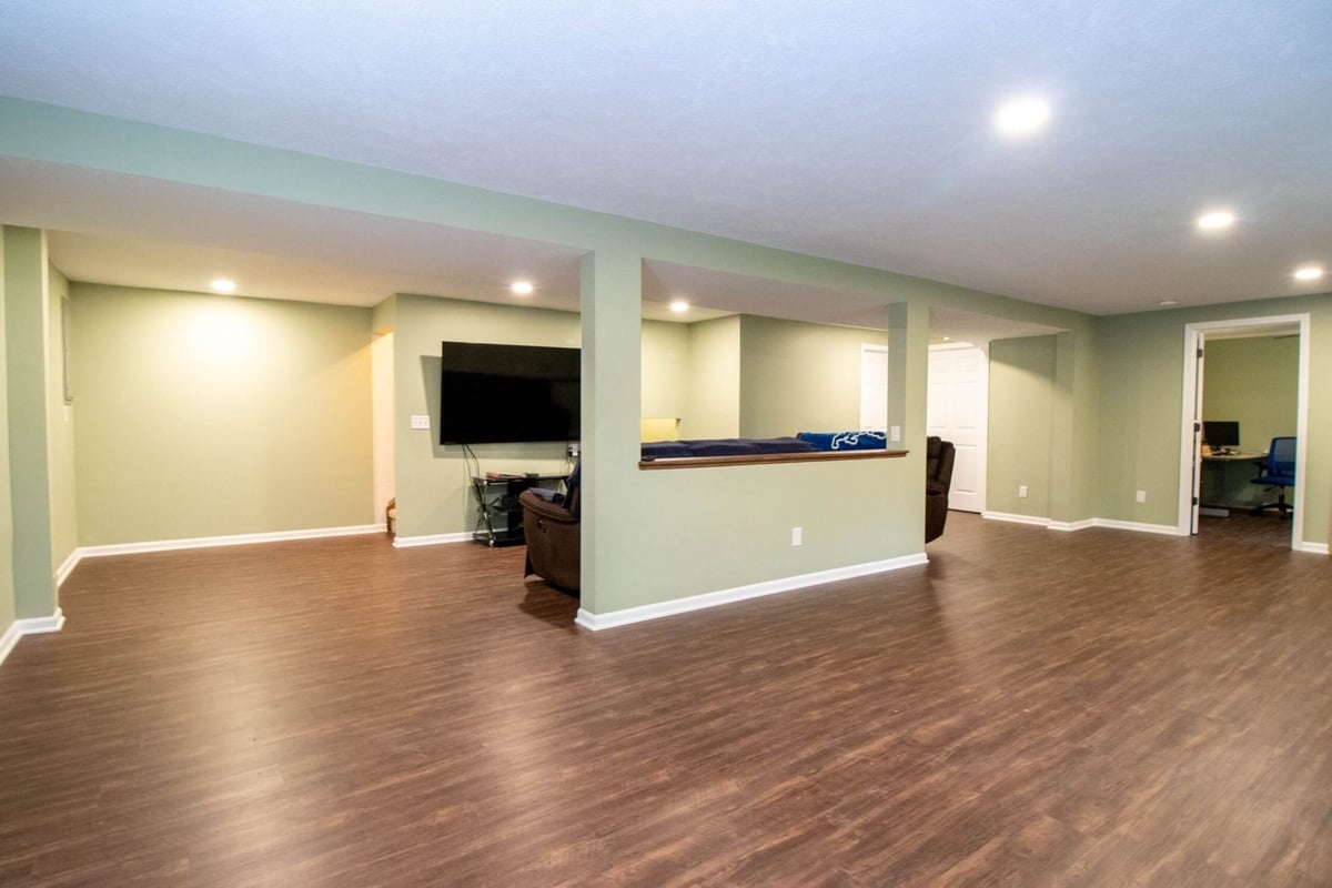 Lansing basement renovation featuring new flooring, recessed lighting, and open living space by Odd Fellows Contracting.