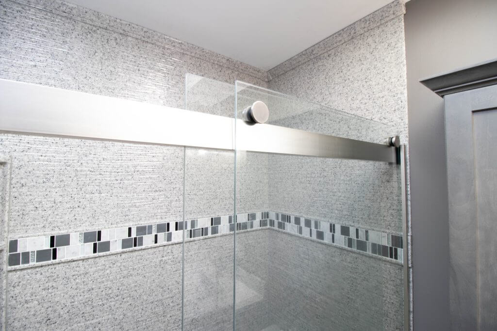 bathroom remodel shower with tile accent band and glass enclosure by Odd Fellows Contracting in Holt, MI