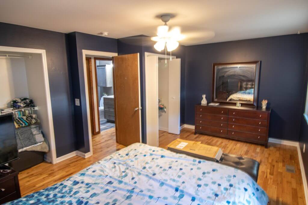 bedroom before renovation with hardwood flooring and closet access by Odd Fellows Contracting in Holt, MI