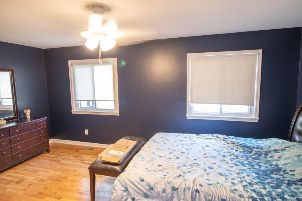 bedroom before renovation with hardwood floors and dark blue walls by Odd Fellows Contracting in Holt, MI