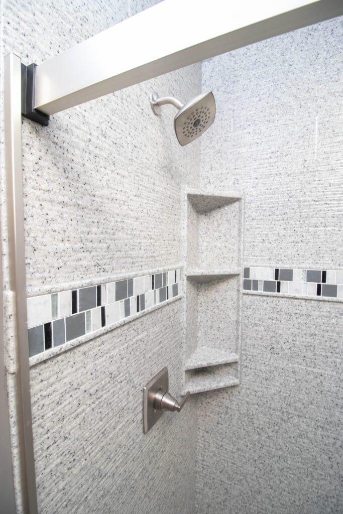 close-up of remodeled shower with tile accent and built-in shelving by Odd Fellows Contracting in Holt, MI