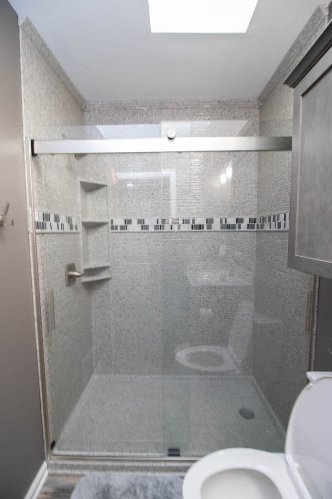 remodeled bathroom shower with sliding glass door and tile surround by Odd Fellows Contracting in Holt, MI