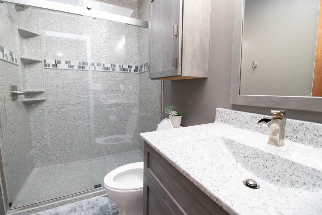 remodeled bathroom vanity with quartz countertop and storage cabinet by Odd Fellows Contracting in Holt, MI