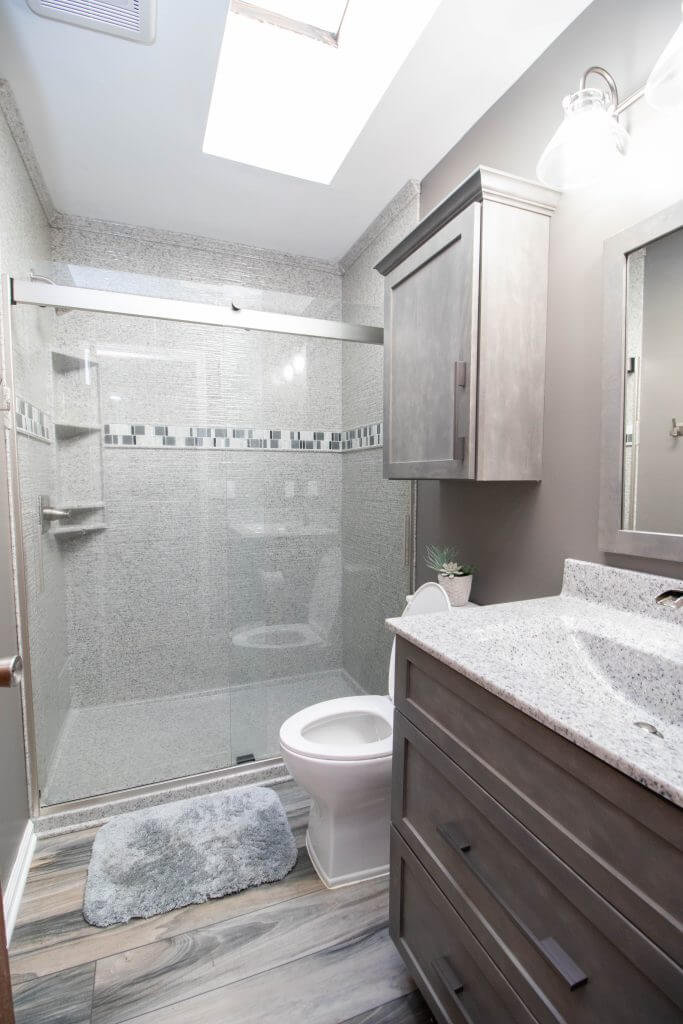 remodeled bathroom with glass shower enclosure and modern vanity by Odd Fellows Contracting in Holt, MI