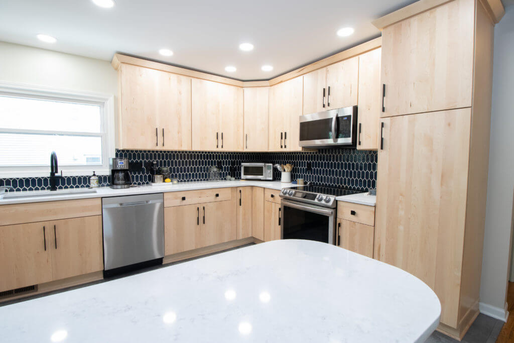 Kitchen renovation with light wood cabinets and dark tile backsplash by Odd Fellows Contracting in East Lansing, MI