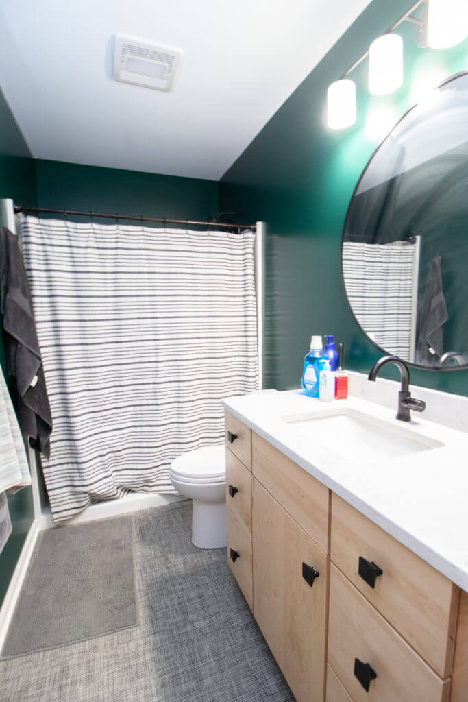 Updated bathroom with wood vanity cabinet and modern fixtures by Odd Fellows Contracting in East Lansing, MI