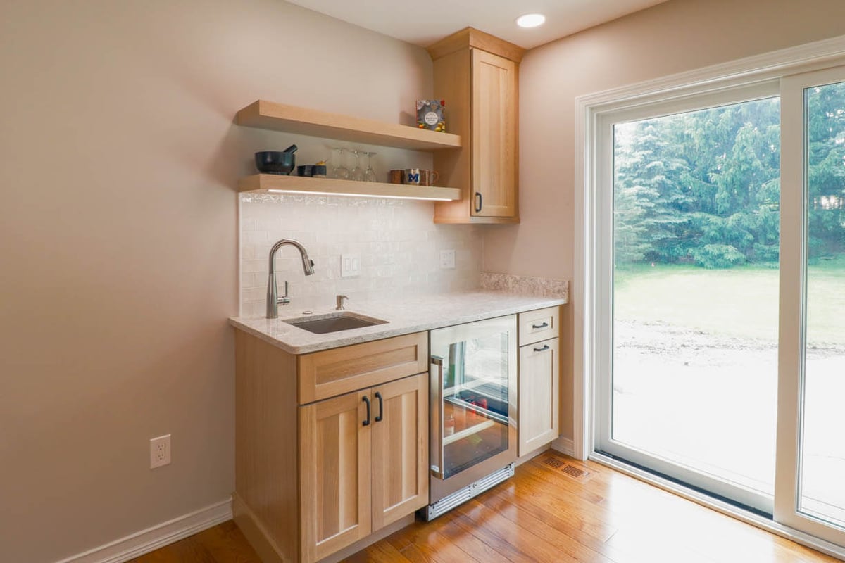 Cornell Woods, MI custom home by Odd Fellows Contracting with modern wet bar, floating shelves, and sliding glass door access.