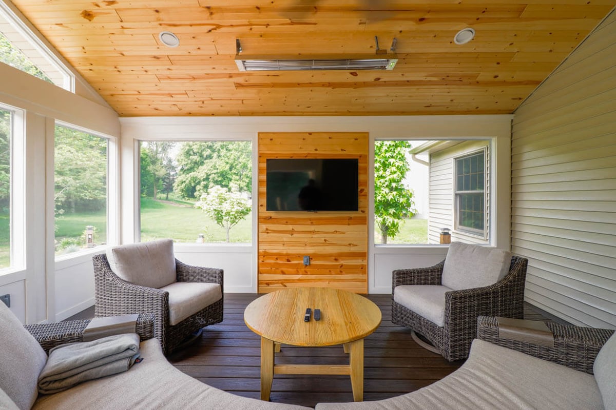 Cornell Woods, MI custom home porch addition by Odd Fellows Contracting featuring vaulted ceiling and mounted television.