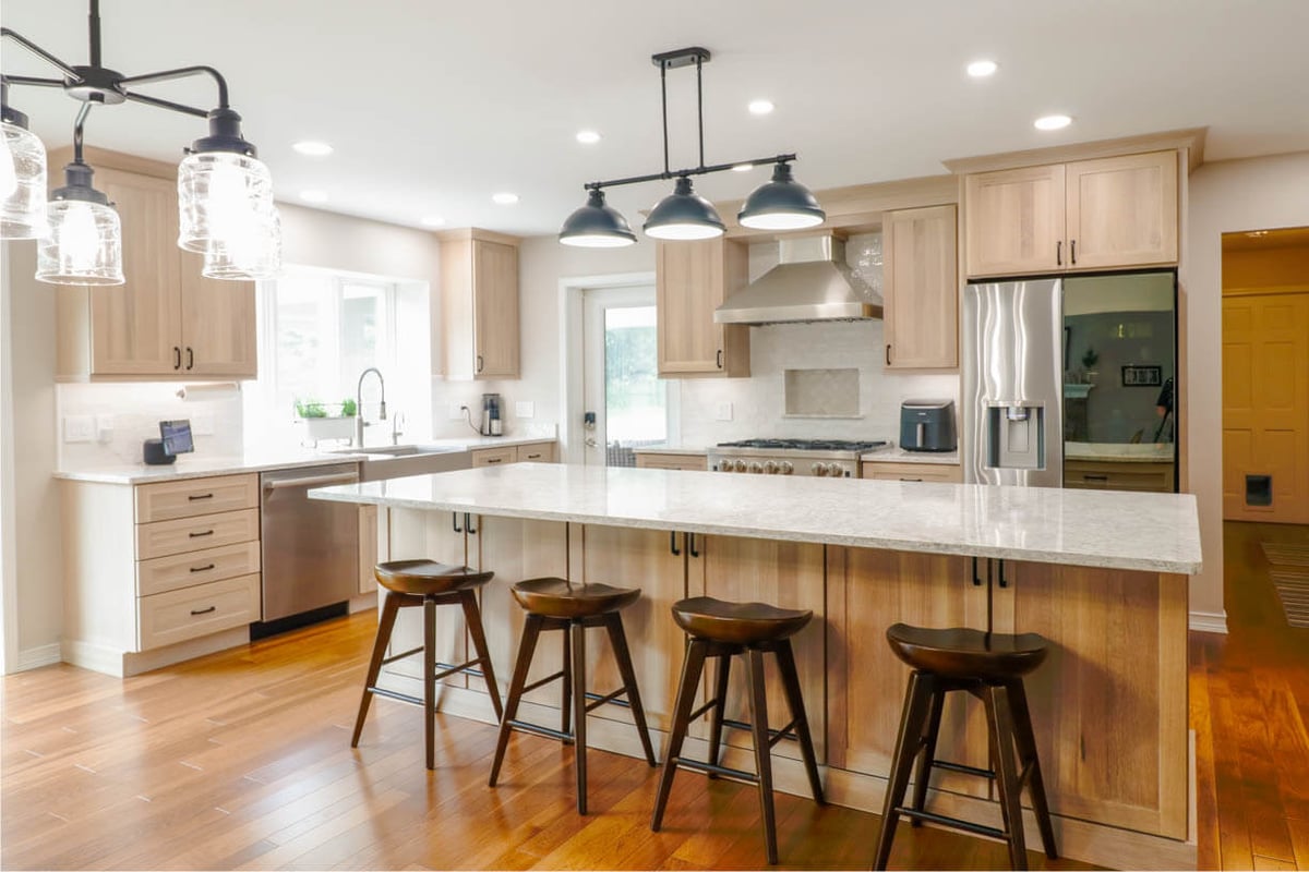Custom home kitchen by Odd Fellows Contracting in Cornell Woods, MI with large island, stainless range, and wood cabinetry.