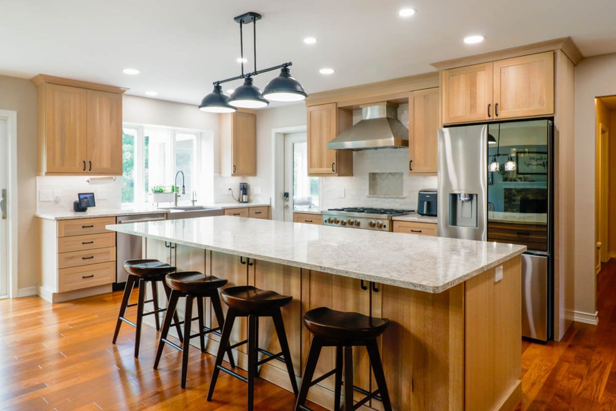 Custom home kitchen island and cabinetry by Odd Fellows Contracting in Cornell Woods, MI with pendant lighting and hardwood floors.