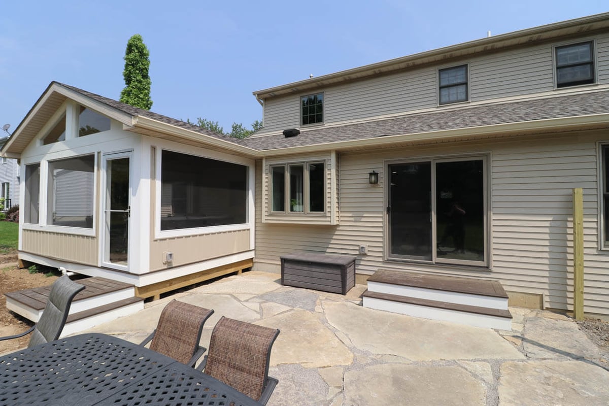 Exterior view of custom home in Cornell Woods, MI by Odd Fellows Contracting featuring porch addition and backyard access.