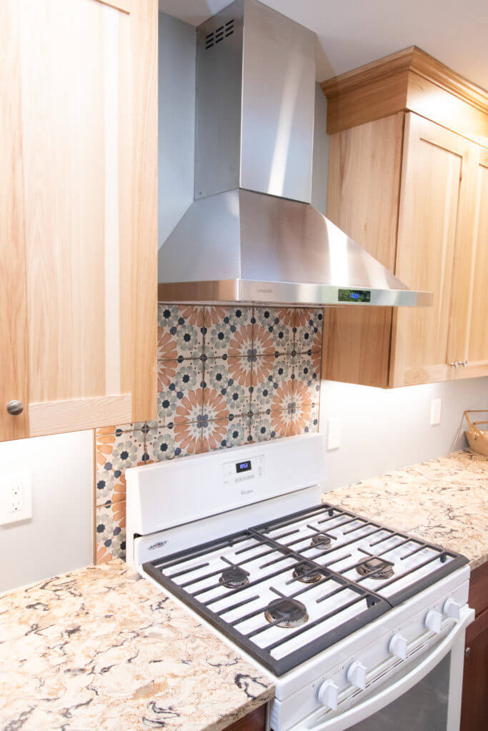 kitchen remodel featuring stainless steel range hood, patterned tile backsplash, and granite countertops by Odd Fellows Contracting in Grand Ledge, MI