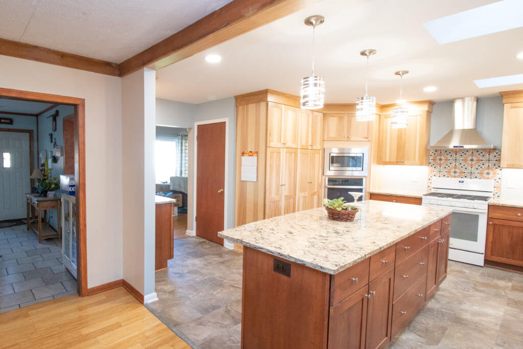 kitchen renovation featuring large island, custom cabinets, and modern lighting by Odd Fellows Contracting in Grand Ledge, MI