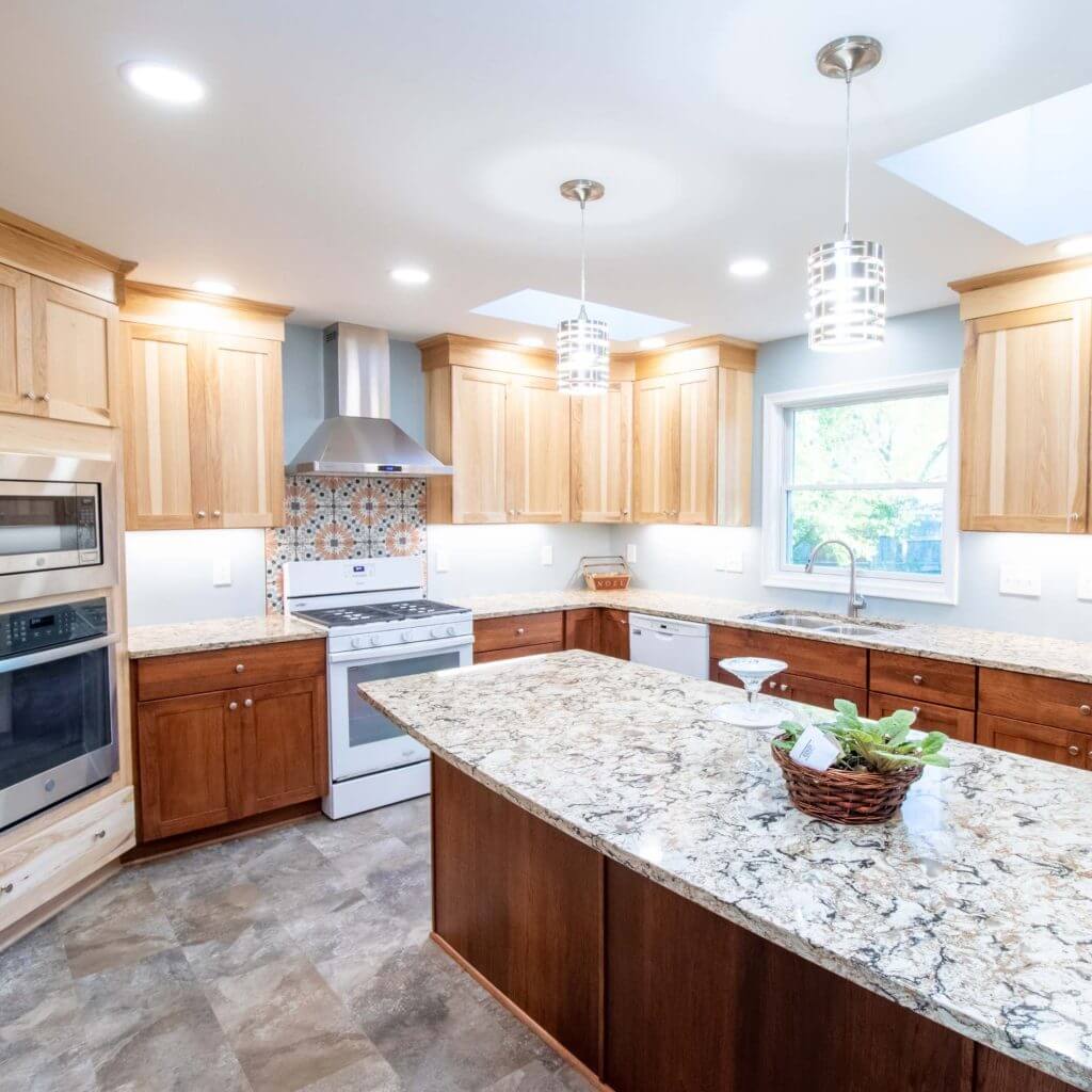 remodeled kitchen with large granite island, custom wood cabinetry, and modern lighting by Odd Fellows Contracting in Grand Ledge, MI