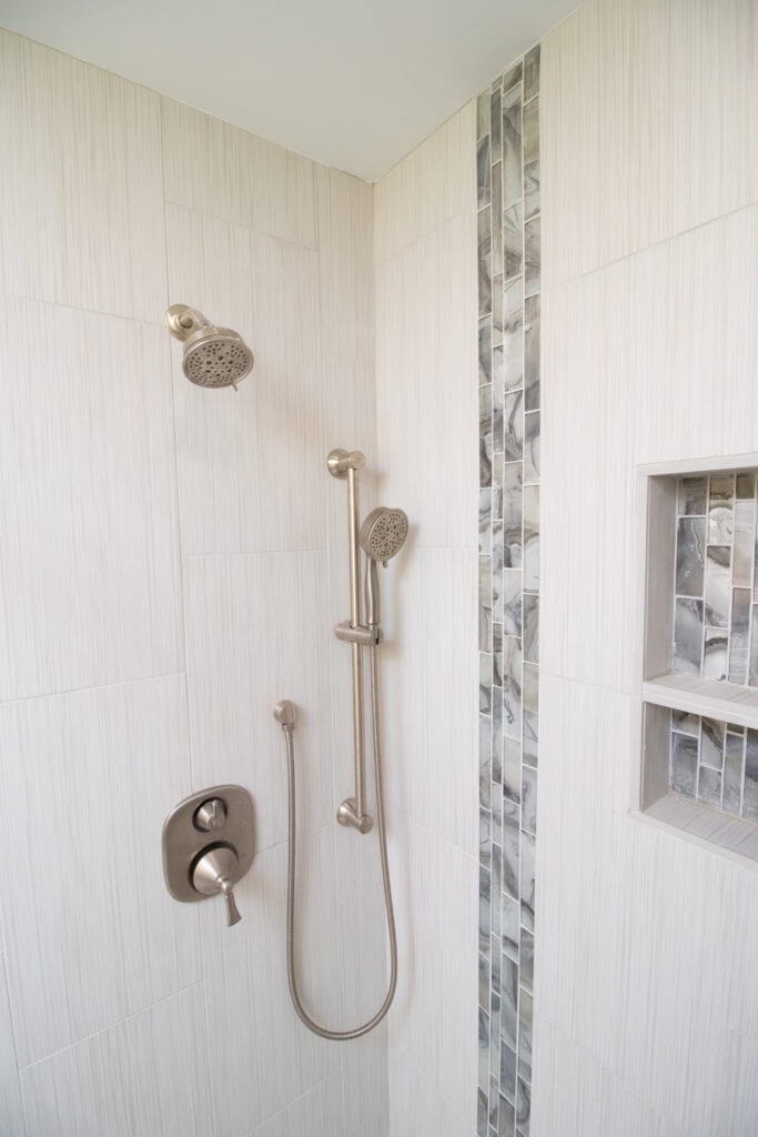 remodeled walk in shower with tiled walls, niche shelving, and handheld shower head by Odd Fellows Contracting in Grand Ledge, MI
