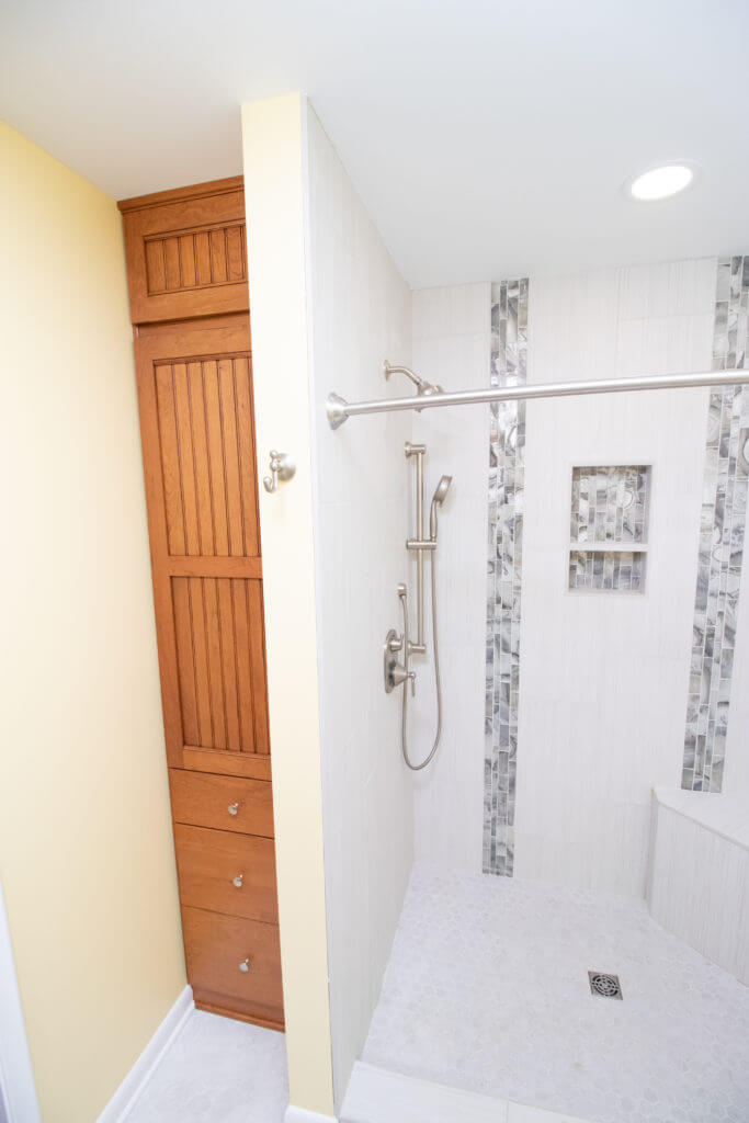 walk in shower remodel with accent tile strip and built in shelving niche by Odd Fellows Contracting in Grand Ledge, MI