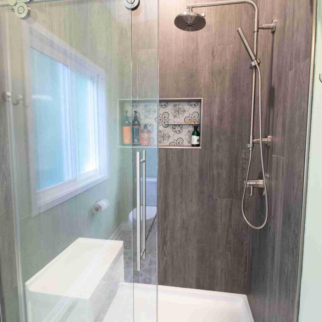 modern shower renovation by Odd Fellows Contracting in Williamston MI with glass door and built-in niche