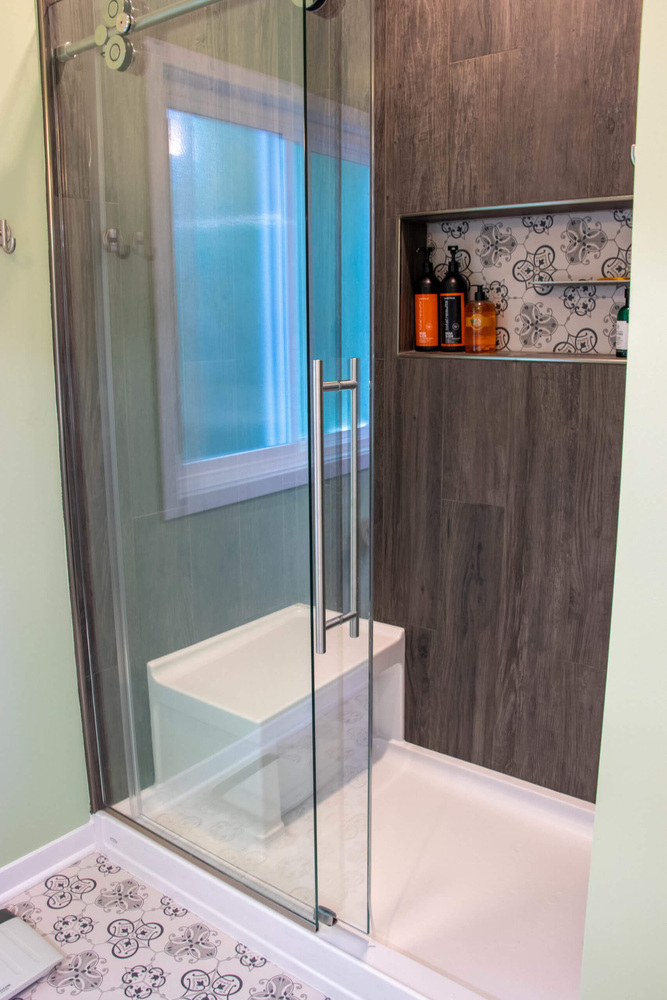 modern walk-in shower by Odd Fellows Contracting in Williamston MI with sliding glass door and bench