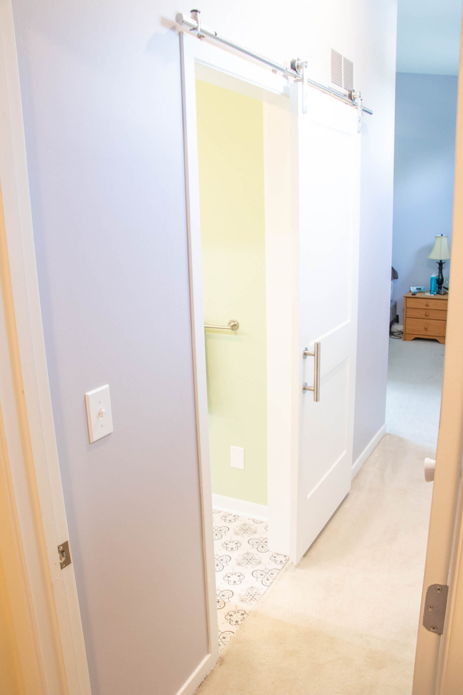 sliding barn door by Odd Fellows Contracting in Williamston MI leading to remodeled bathroom
