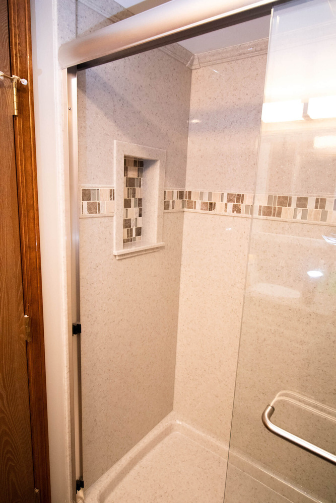 custom shower remodel by Odd Fellows Contracting in Mason MI with glass door and tiled niche