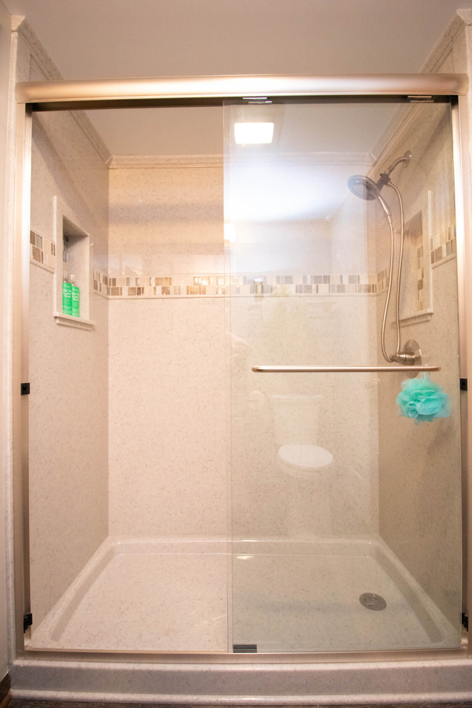 walk in shower remodel by Odd Fellows Contracting in Mason MI with glass doors and built in shelving
