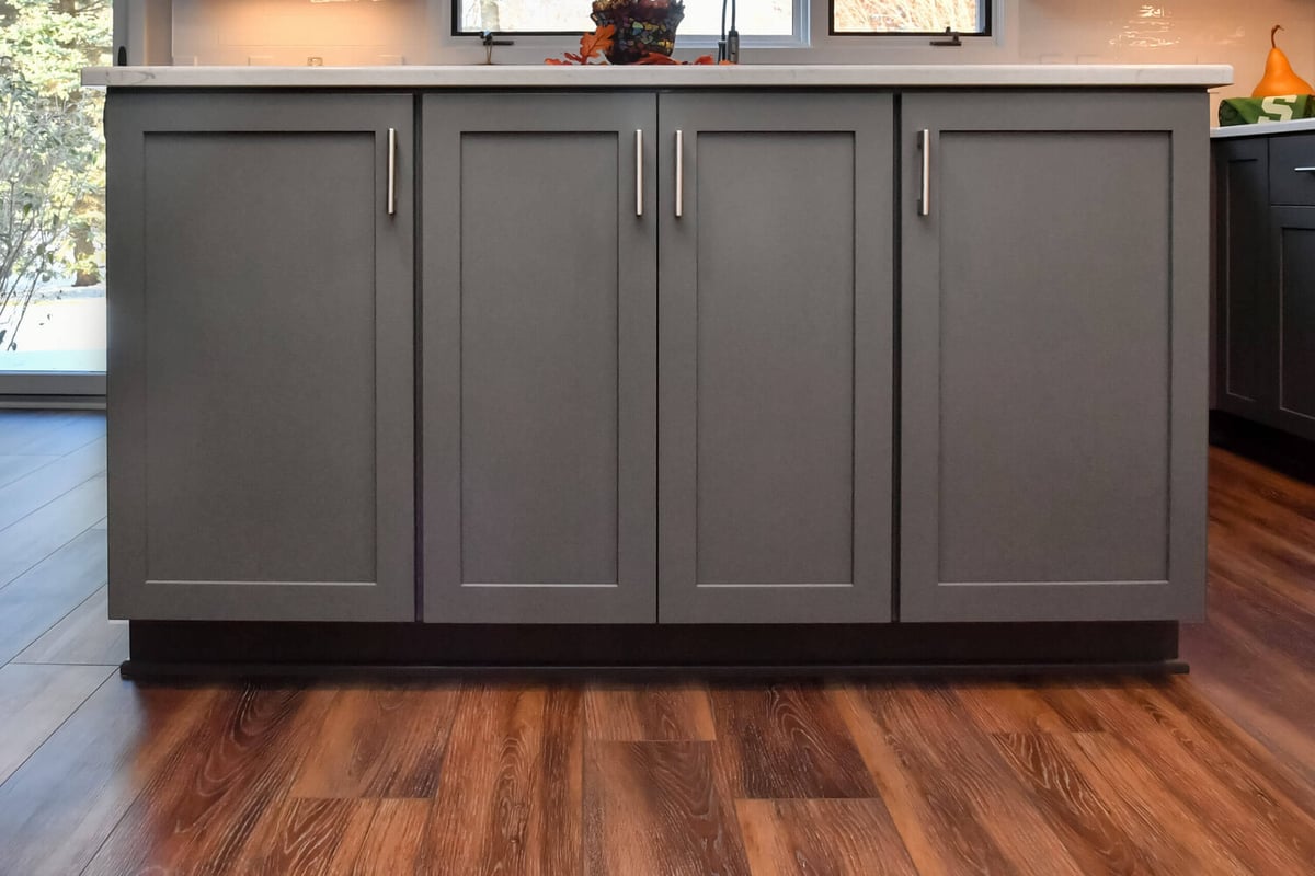 Kitchen island with gray cabinet base and quartz countertop by Odd Fellows Contracting in Okemos, MI