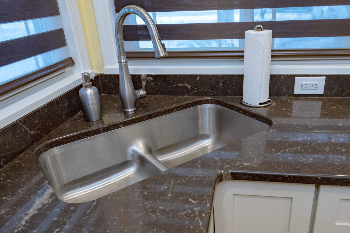 kitchen remodel detail showing stainless sink and faucet with quartz countertop by Odd Fellows Contracting in Lansing, MI