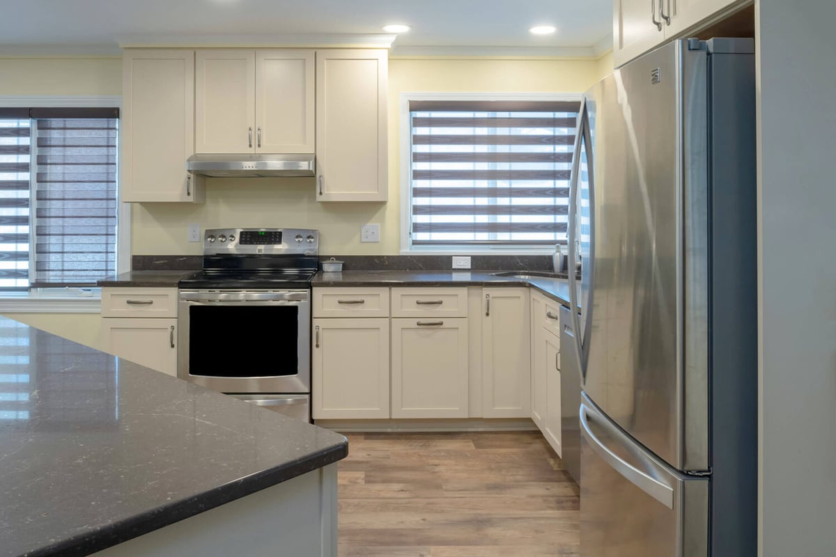 kitchen remodel with quartz island, stainless steel range, and white shaker cabinets by Odd Fellows Contracting in Lansing, MI