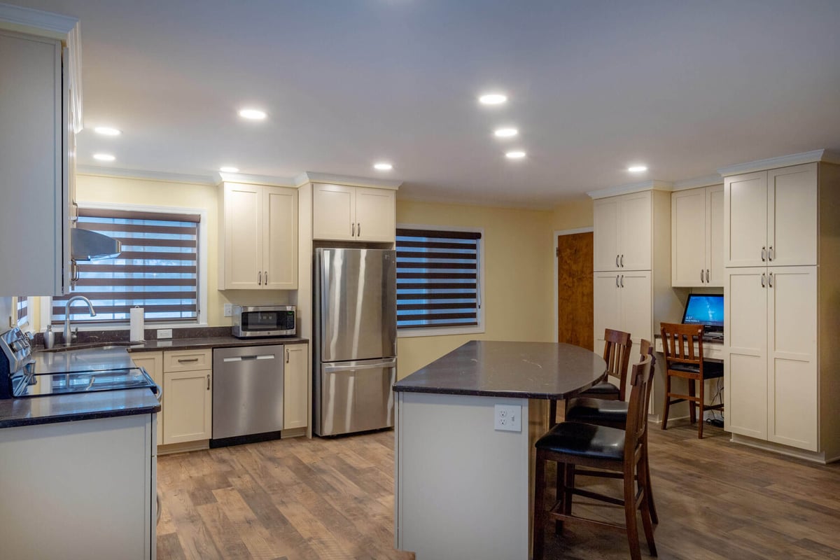 open concept kitchen remodel with large quartz island, stainless appliances, and white shaker cabinets by Odd Fellows Contracting in Lansing, MI