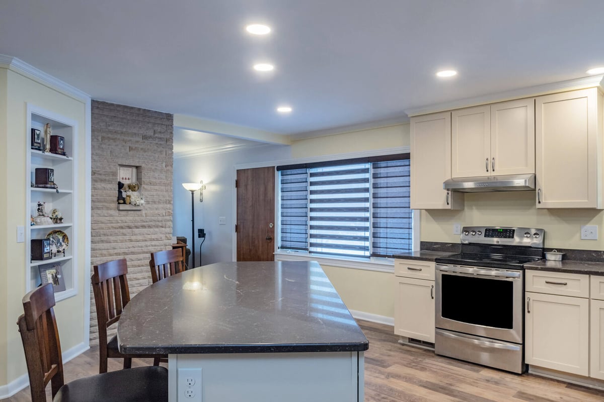 remodeled kitchen with quartz island and white cabinets by Odd Fellows Contracting in Lansing, MI