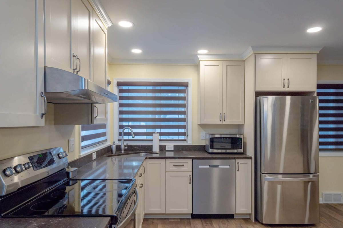 remodeled kitchen workspace with stainless range, dishwasher, and white shaker cabinetry by Odd Fellows Contracting in Lansing, MI