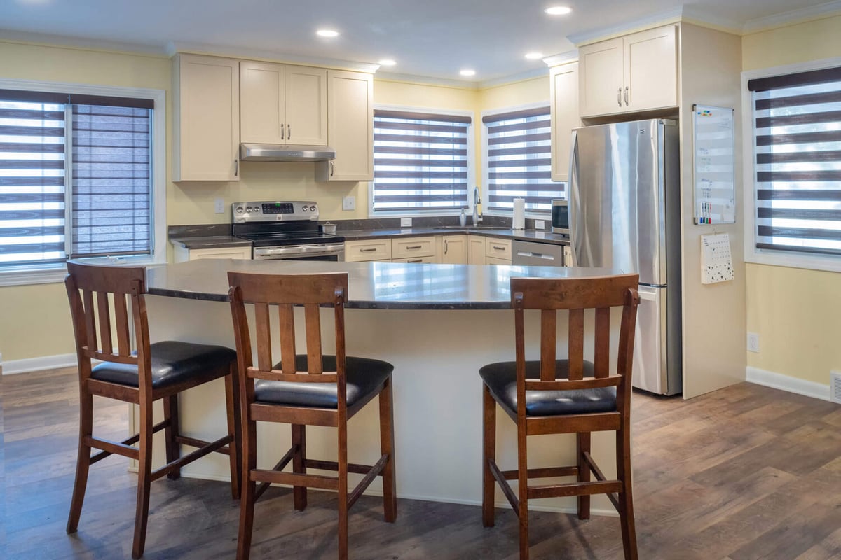 renovated kitchen with island bar seating, stainless appliances, and modern cabinets by Odd Fellows Contracting in Lansing, MI