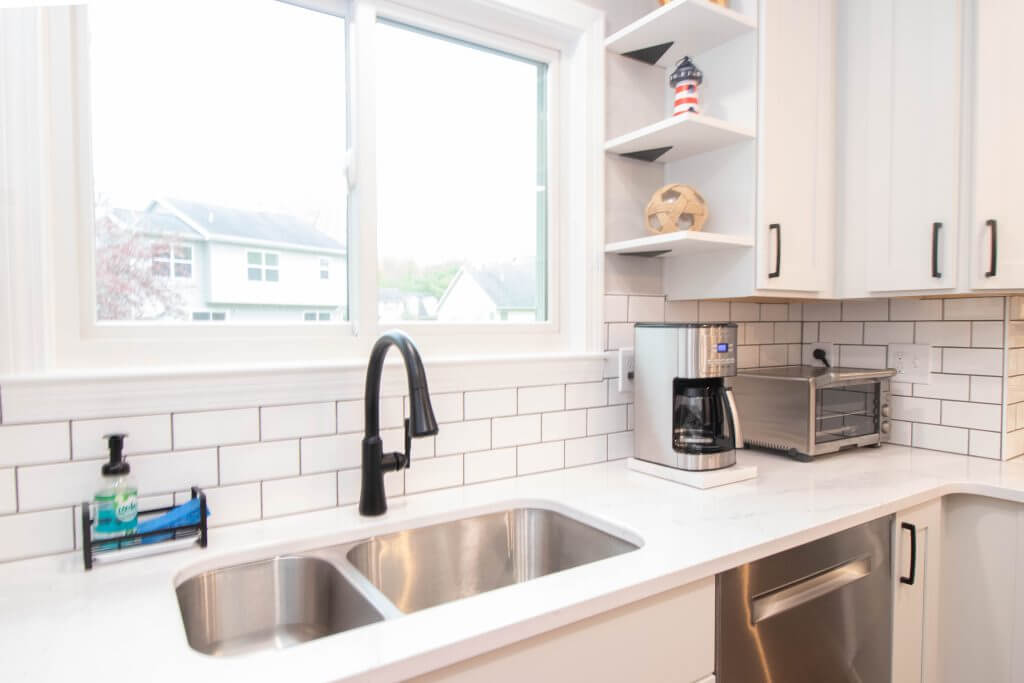 kitchen renovation featuring white cabinets and updated sink under window by Odd Fellows Contracting in Cumberland Lansing MI