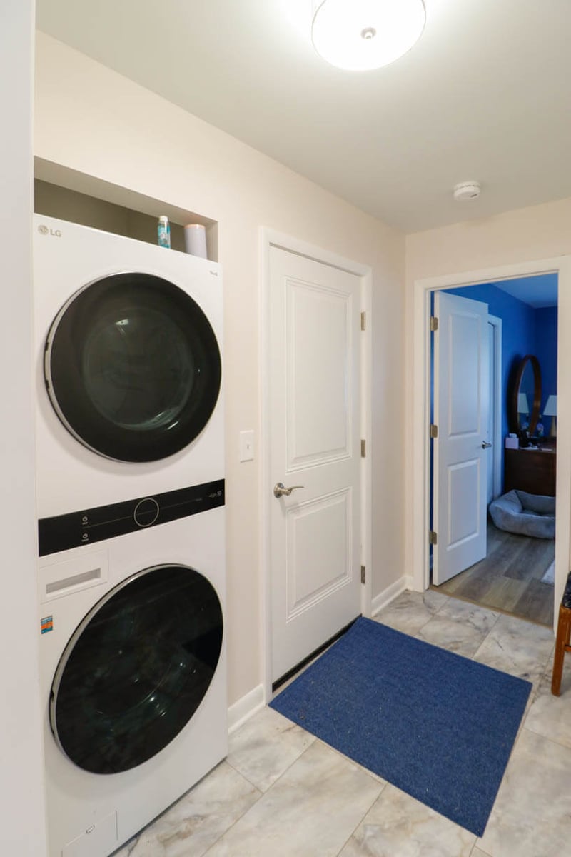 custom home laundry area by Odd Fellows Contracting in Cornell Okemos, MI with stacked washer and dryer