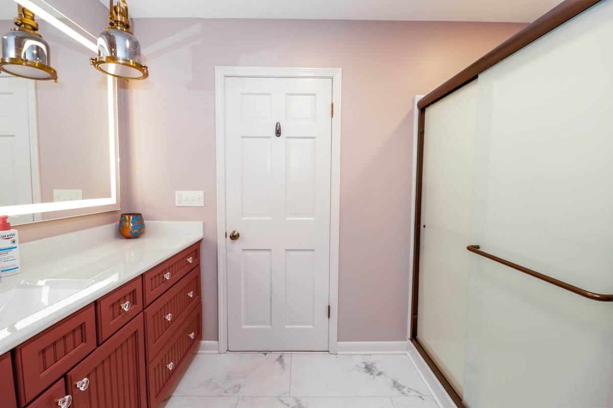 Bathroom remodel in a Tacoma Hills, MI custom home by Odd Fellows Contracting with red vanity and glass shower enclosure.