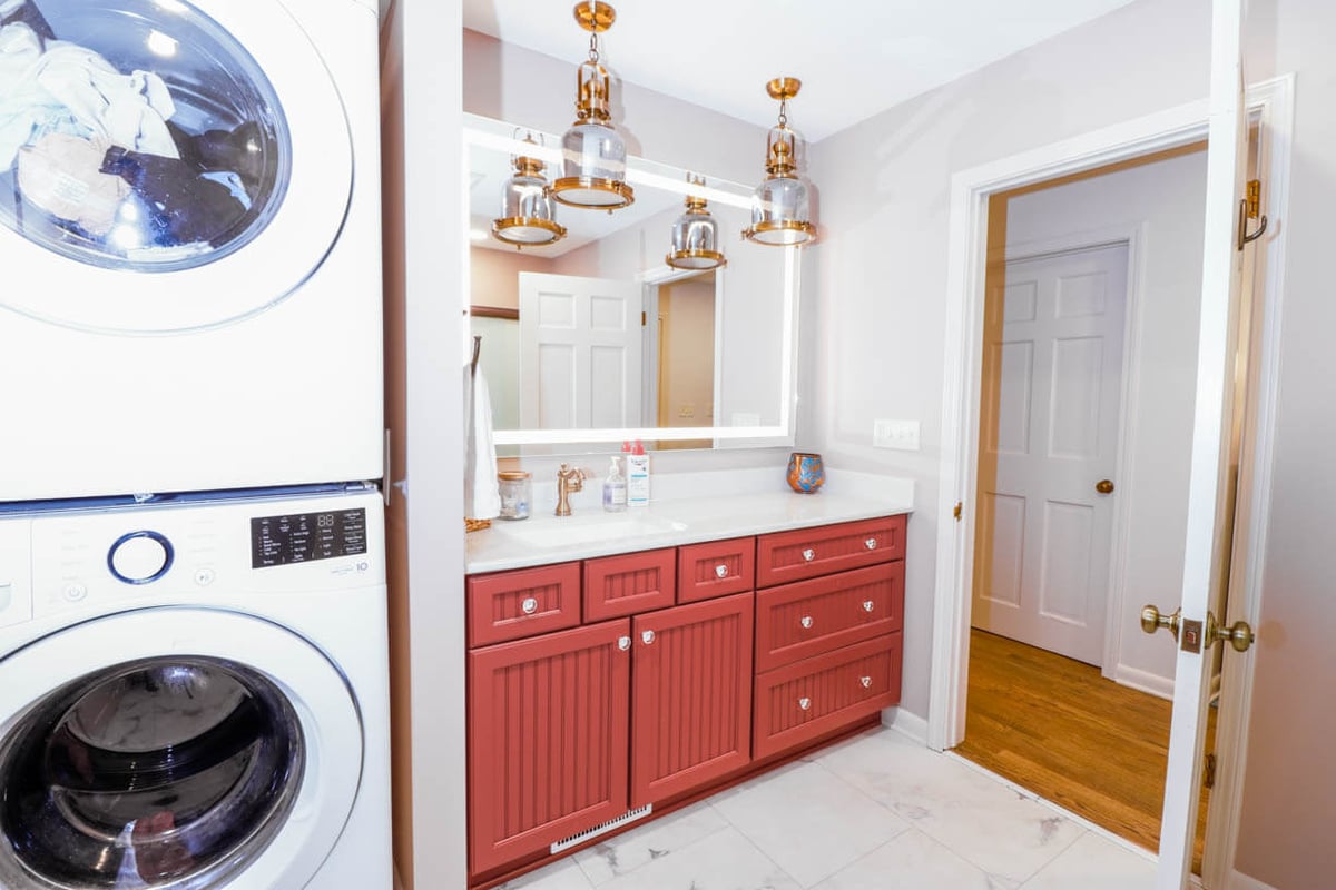 Laundry and vanity area in a Tacoma Hills, MI custom home by Odd Fellows Contracting with red cabinets and quartz countertop.